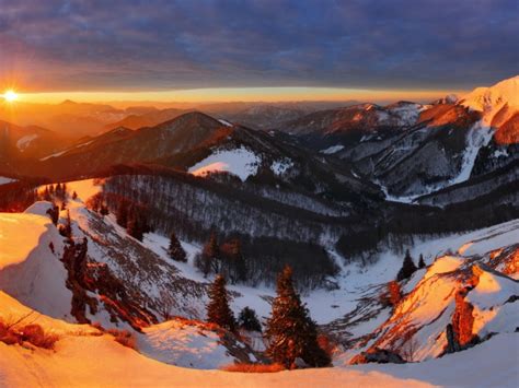 Snow Covered Mountains Covered With Trees In The Sun At Sunset