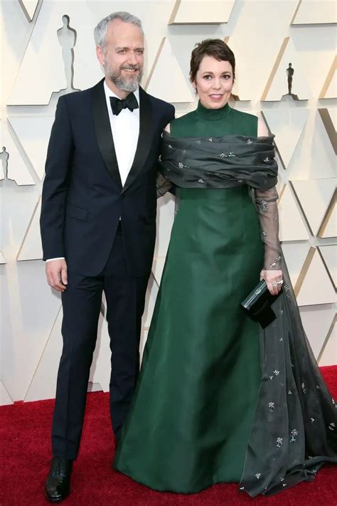 An Older Man And Woman In Formal Wear Posing For The Camera On The