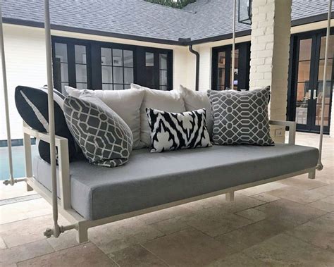 A Porch Swing With Pillows On It In Front Of A House