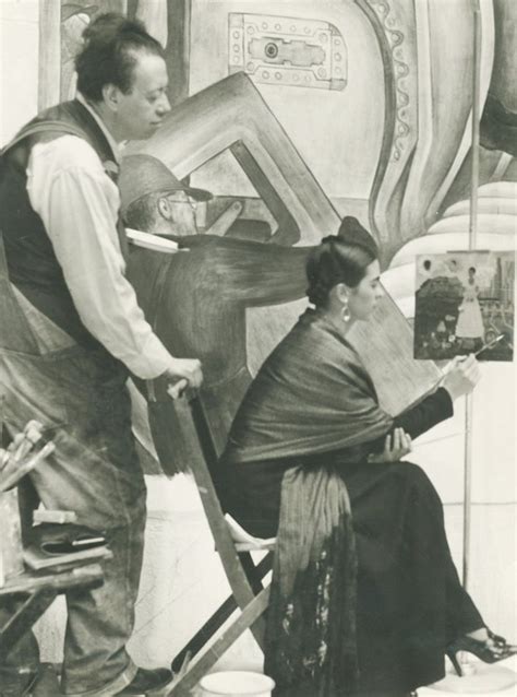 An Old Black And White Photo Of A Woman Sitting In A Chair With A Man Standing Next To Her