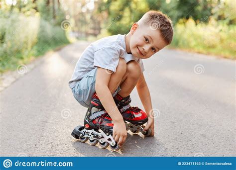 Boy In Roller Skating Sitting On The Road Looking At Camera With Smile