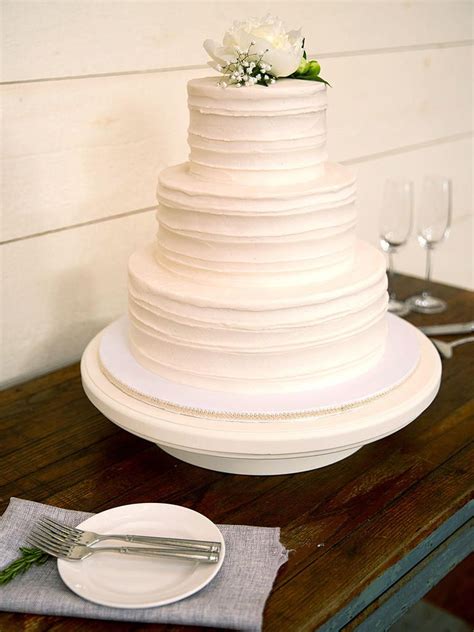 A Three Tiered White Cake Sitting On Top Of A Table Next To A Plate