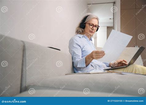 Concentrated Gray Haired Woman Reads A Summary At Home On Couch Stock Image Image Of