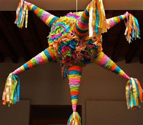 A Multicolored Sculpture Hanging From The Ceiling With Tassels On Its Legs
