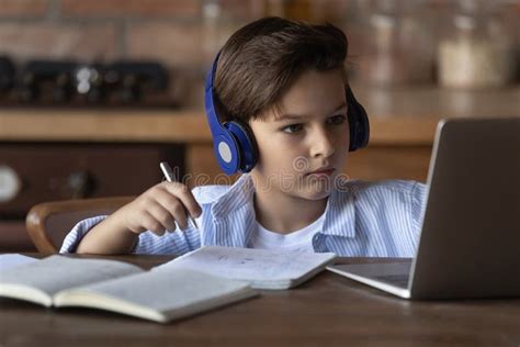 Close Up Little Boy In Wireless Headphones Studying Online Stock Photo