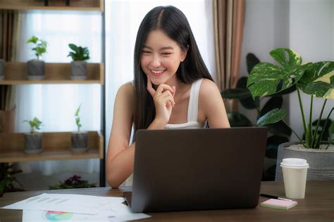 Asian Girl Typing Data To Her Computer Notebook For Prepare Her Report On The Wooden Deak With