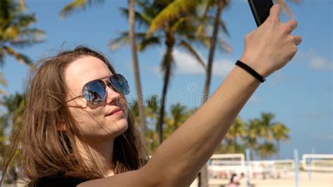 jovem que leva uma selfie debaixo de palmeiras na praia imagem de stock imagem de menina