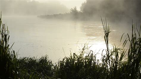 Early Morning Sunrise Reflections In Misty Fog On Flowing River Water