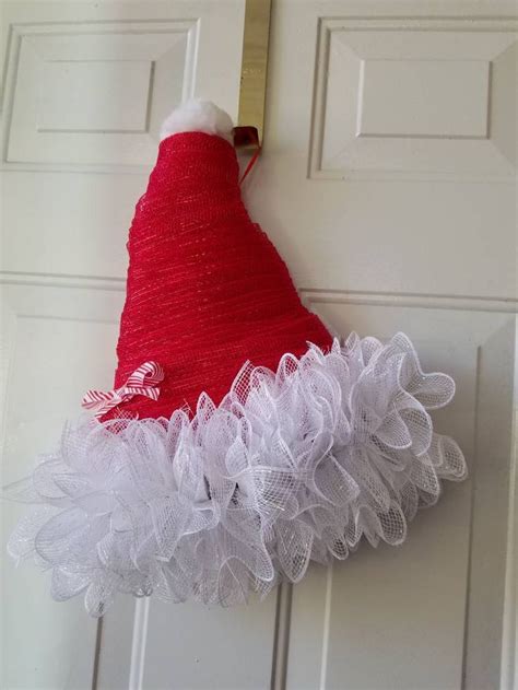 A Red And White Christmas Hat Hanging On A Door Handle With Tulle Ruffles