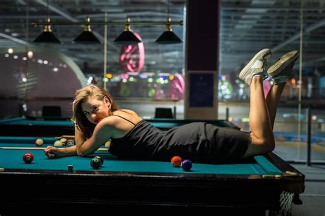 premium photo beautiful woman in elegant black dress lying on the billiard table