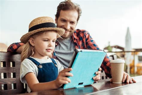 Selective Focus Of Little Girl Using Tablet While Father Sitting Stock