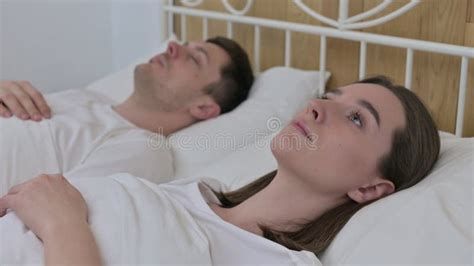 Beautiful Woman Awake In Bed Next To Sleeping Partner Stock Photo