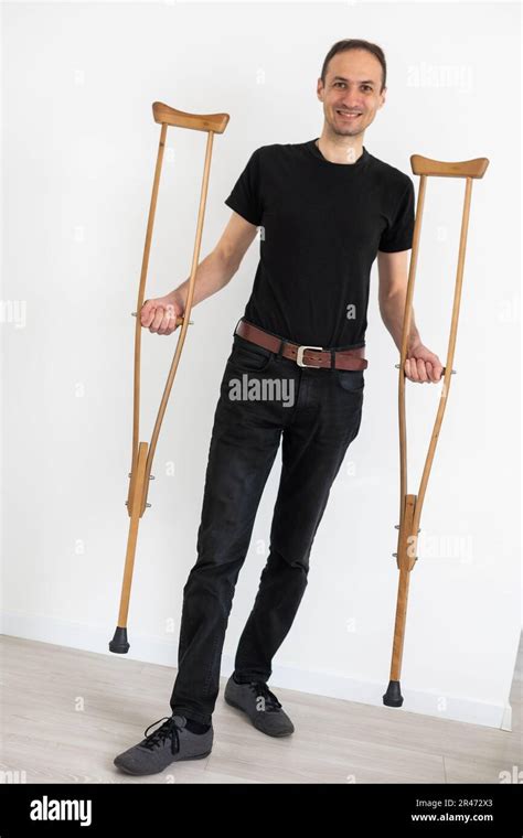 Full Length Portrait Of An Injured Young Man On Crutches Isolated On