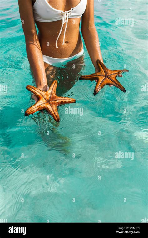 Woman Holding Two Red Starfish On Turquoise Water Background Travel And Vacation Concept Stock