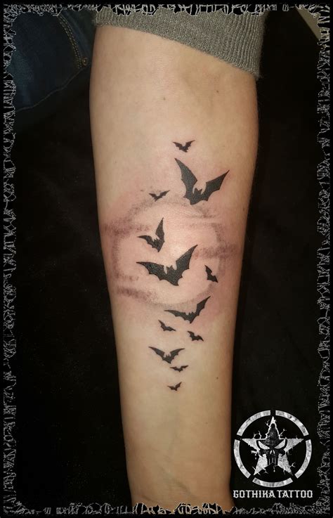 A Person With A Tattoo On Their Leg That Has Bats Flying In The Sky