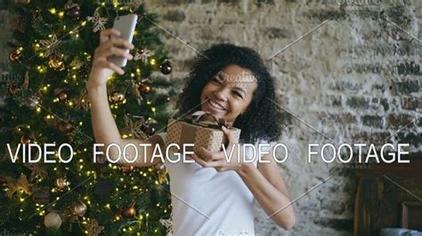 Funny Mixed Race Girl Taking Selfie Pictures On Smartphone Camera At Home Near Christmas Tree