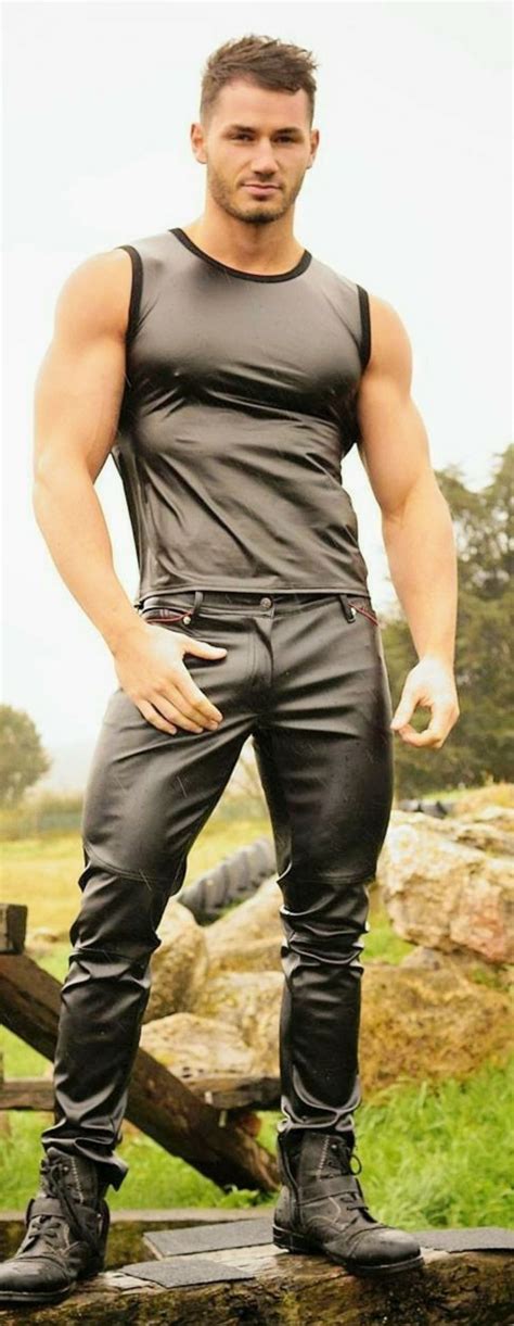 A Man Is Posing For A Photo In Black Leather Pants And Tank Top With