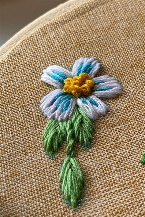 An Embroidered Flower On The Back Of A Chair With Green And Yellow