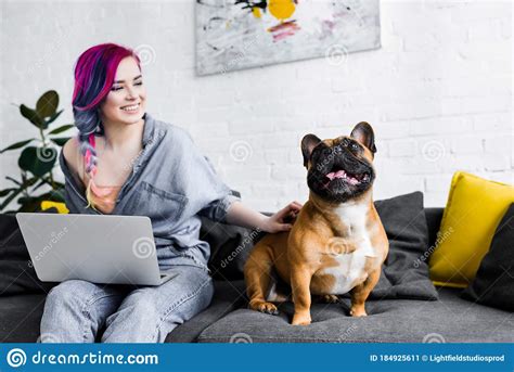 Girl With Colorful Hair Sitting On Sofa Using Laptop And Petting