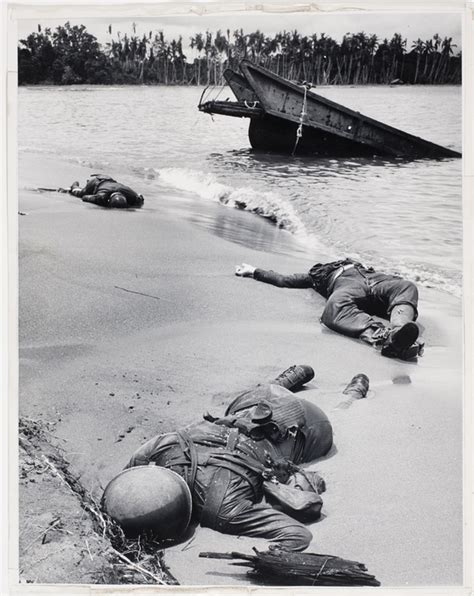 Bodies Of Three Dead American Soldiers Lying In The Sand On Shoreline