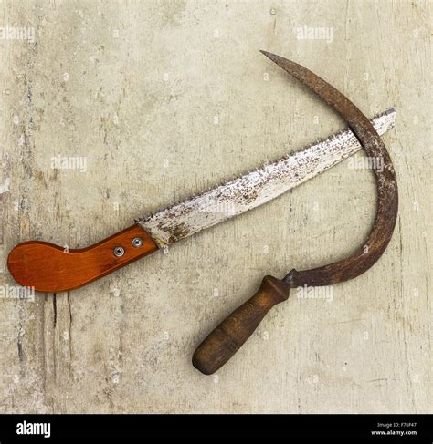 One Rusty Scythe And One Small Saw On A Grunge Background Stock Photo