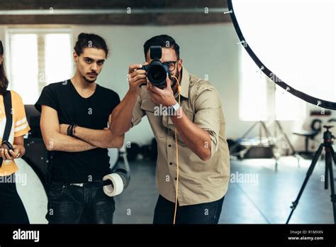 Photographer With His Team Doing A Photo Shoot In A Studio