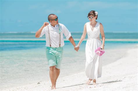 Bride and groom holding hands while walking on seashore · Free Stock Photo