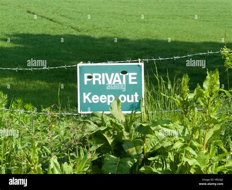 Private Keep Out Sign On Barbed Wire Boundary Fence To Farmland Stock