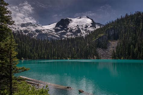 A Lake Surrounded By Trees And Snow Covered Mountains