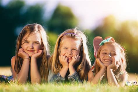 Drie Glimlachende Meisjes Die Op Het Gras In Het Park Leggen Stock Foto Image Of Buiten