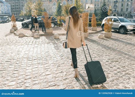 Young Beautiful Woman Walking Along City Street With Travel Suitcase