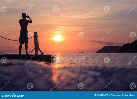 Asian Man Standing And Jumping On Floating Pier At Sunrise Silhouette