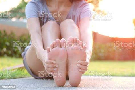 발 통증 그 발을 잡고 공원에 잔디에 앉아 남자의 다리 그리고 아침 햇빛에 근육을 스트레칭 건강 관리 및 스파 개념 다리 신체