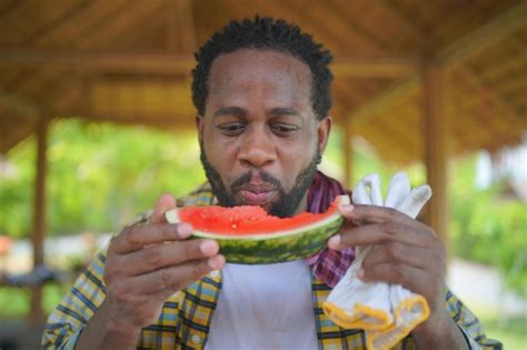 premium photo afro man eating watermelon at farm