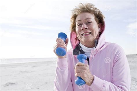 Senior Woman Exercising With Hand Weights On Beach Stock Photo Image