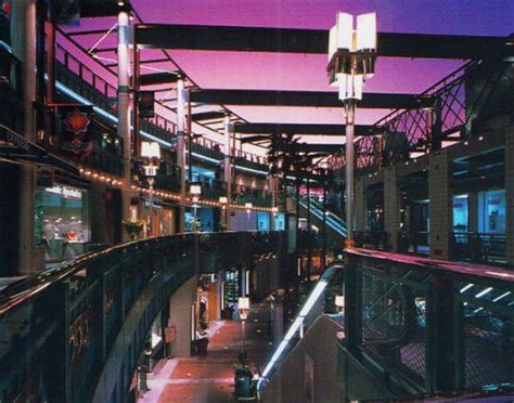 The Inside Of A Shopping Mall With Lights And Escalators