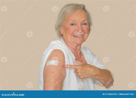 une dame âgée montrant un plâtre sur son bras couvrant son site de vaccination image stock