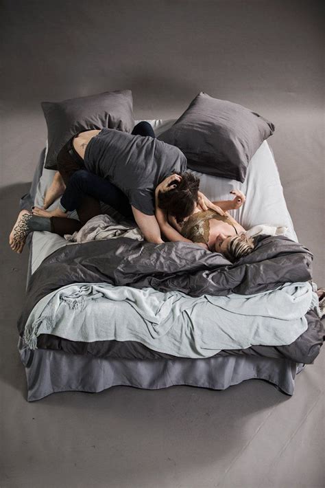 Two People Laying On Top Of A Bed With Pillows