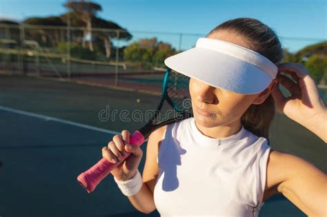 Young Female Caucasian Tennis Player Wearing White Visor Cap Holding