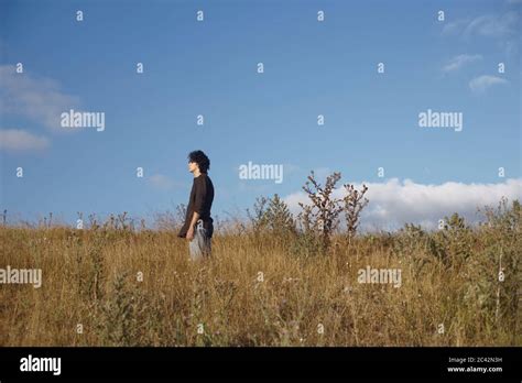 Young Man Is Standing In A High Grass Field Stock Photo Alamy