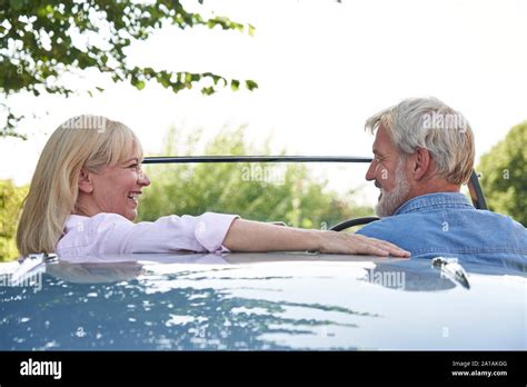 Rear View Of Mature Couple Enjoying Road Trip In Classic Open Top Sports Car Together Stock
