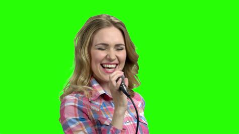 Charming woman singing in microphone on green screen ...