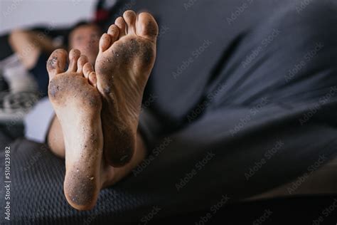 Unrecognizable Man Lying On The Sofa With The Soles Of His Feet Dirty