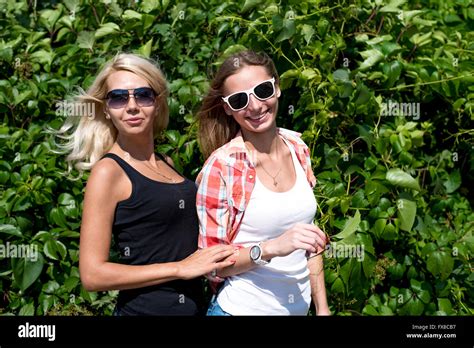 Two Girls Posing In The Green Bushes Glasses Blonde And Brunette