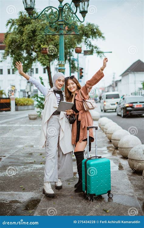 Two Excited Travellers Raising Their Hands While Standing Together At