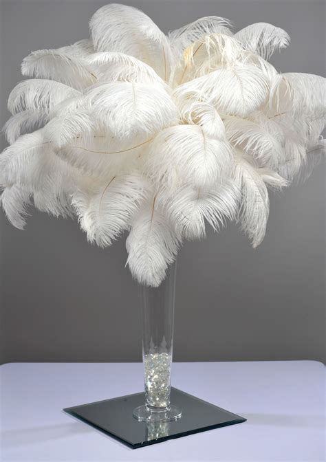 A Vase Filled With White Feathers On Top Of A Table