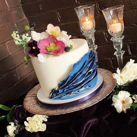 A Three Tiered Cake With Flowers And Blue Ribbon On Top Sits Next To