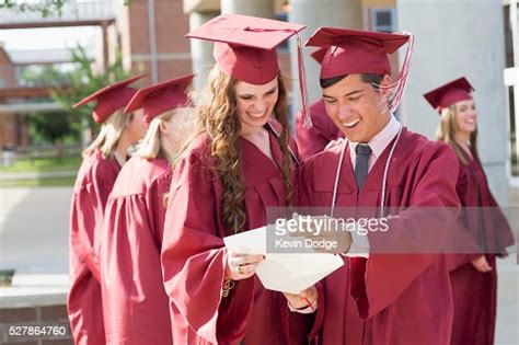 Happy High School Graduates Looking At Diploma High Res Stock Photo