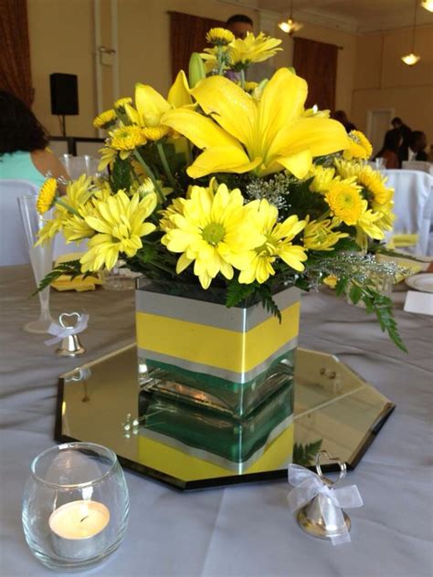 A Vase Filled With Yellow Flowers Sitting On Top Of A Table Next To A