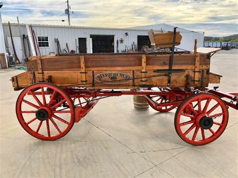 An Old Fashioned Wooden Wagon Is Parked In Front Of A White Building
